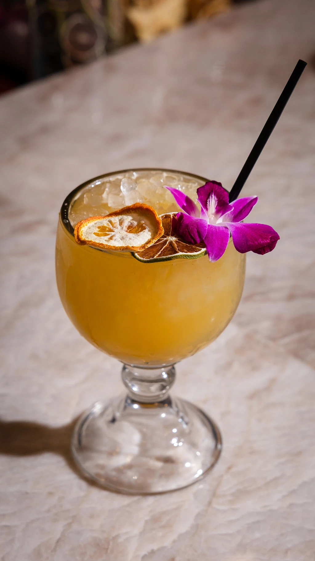 A Mi Rancho cocktail with a lime wheel and orchid garnish